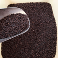 Black rice in a metal scoop against a cream background
